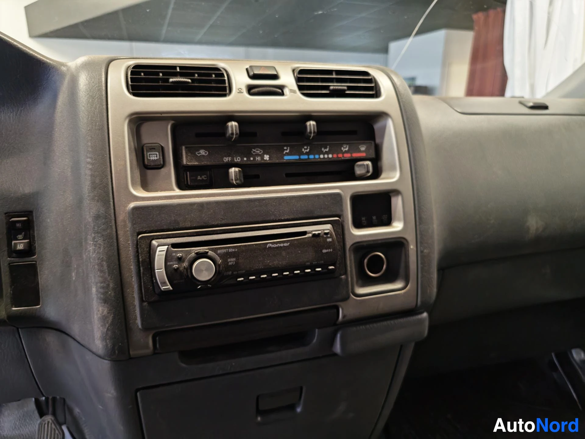 Ohjaamo: Kojelaudan keskikonsoli: ilmastointipaneeli A/C-painikkeella ja Pioneer-autoradio.