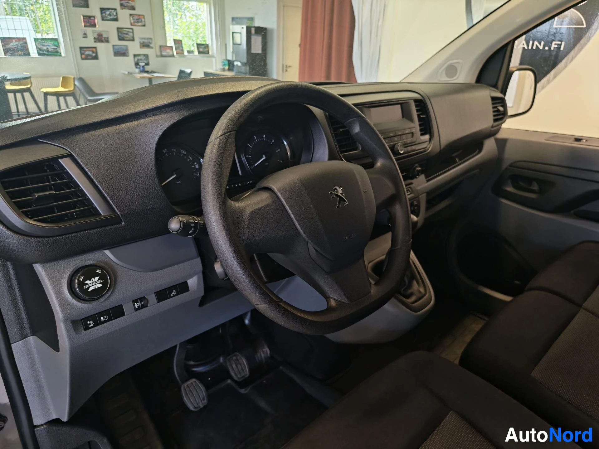 Muu: Ohjaamo näkyy ohjauspyörän kohdalta; kojetaulu, mittaristo ja vaihdekeksi näkyvät, Peugeot-logon ohjauspyörässä.