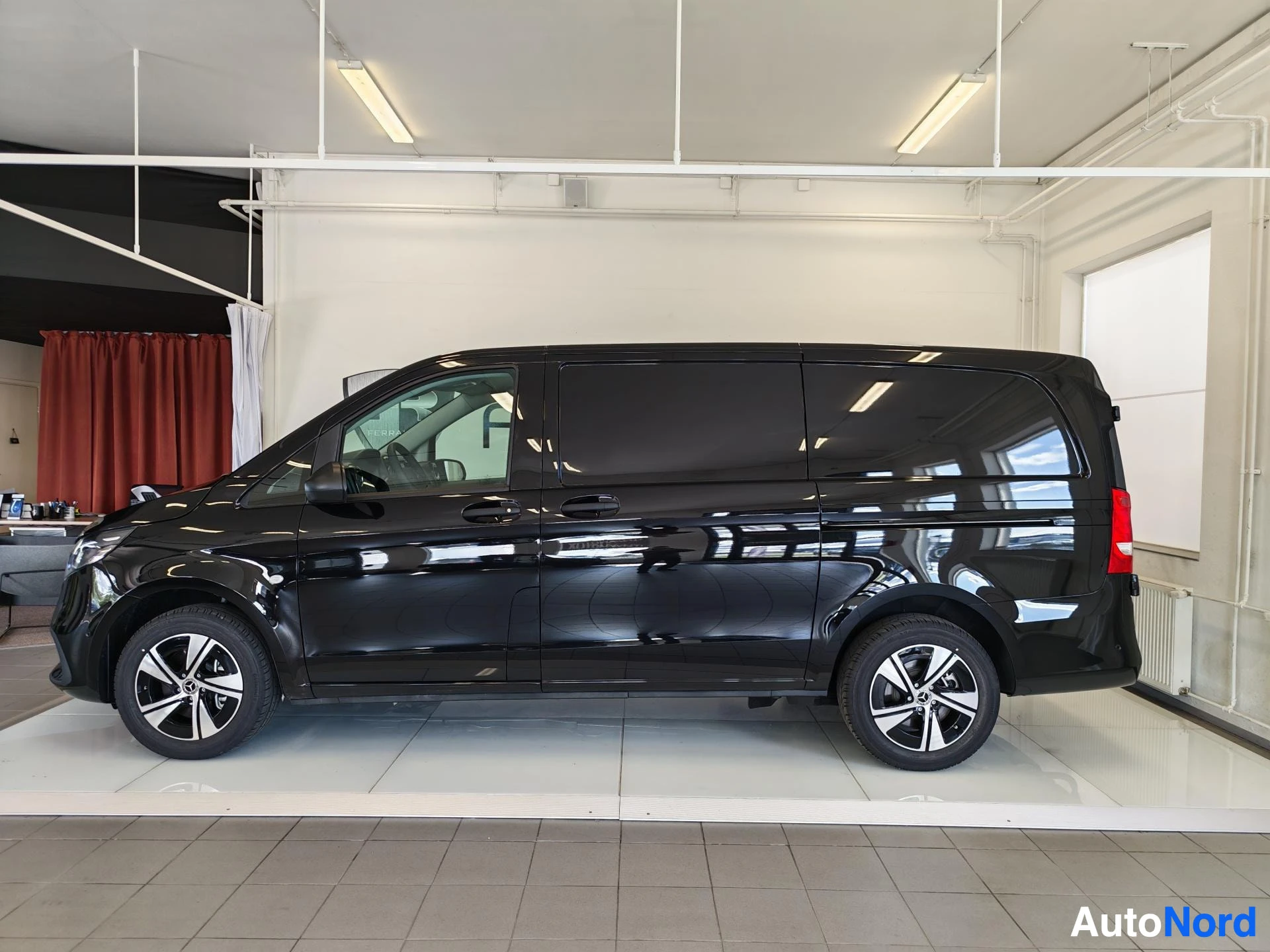 Sivulta: Musta Mercedes-Benz Vito -pakettiauto sivulta oikealta autosalissa.