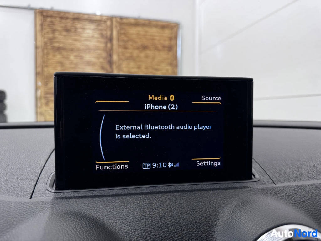 Muu: Auton kojetaulun näyttö Media-näkymässä: teksti 'iPhone (2)' ja 'External Bluetooth audio player is selected', kellonaika 9:10.