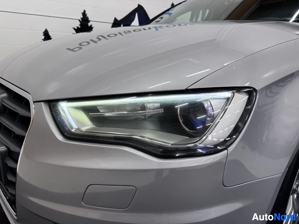 Edestä: Hopeanharmaan Audi A3:n etupää lähikuvassa: etusäleikkö jaXenon-tyylinen etuvalo näkyvät tarkasti sisätiloissa valokuvattuna.