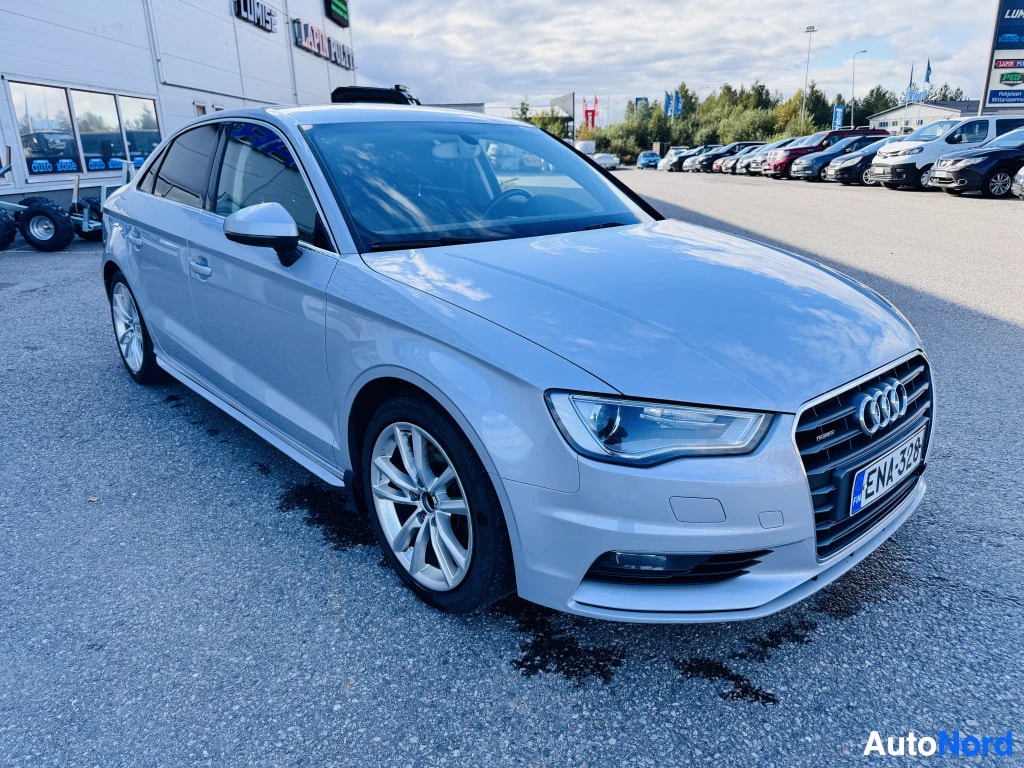 Etuviisto, nokka oikealle: Audi A3 -sedan etukulmasta oikealta, hopeanvärinen korimalli parkkipaikalla.