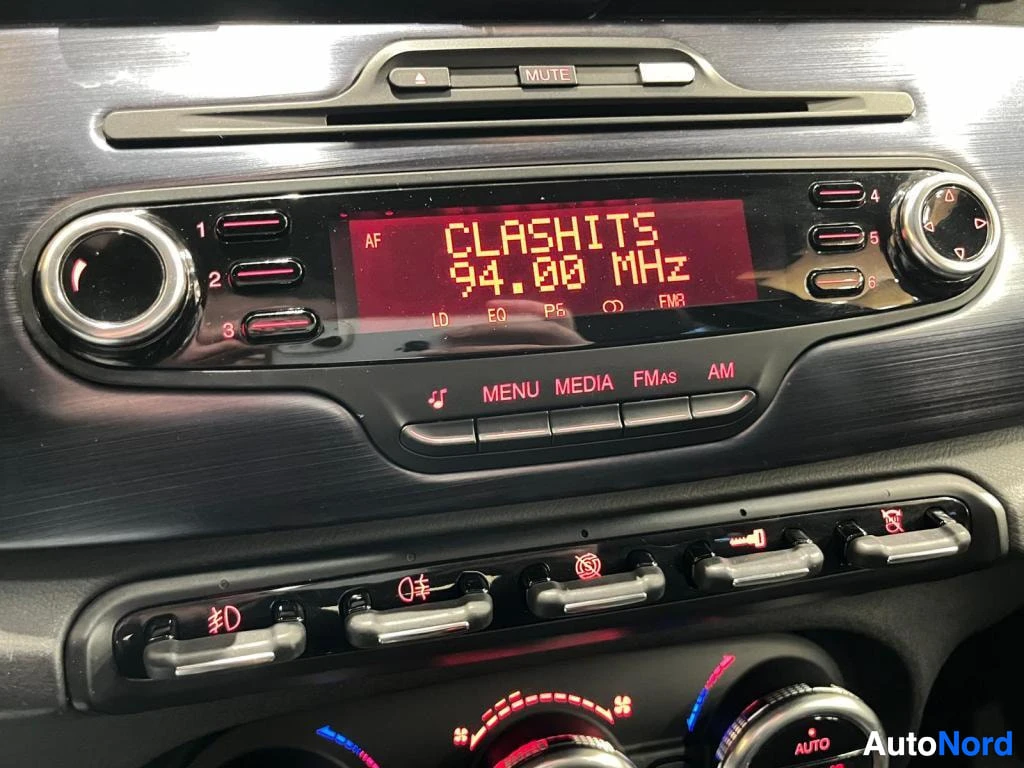 Muu: Radiopaneeli, jonka näytössä teksti CLASHITS 94.00 MHz, alla MUTE, MENU, MEDIA, FMAS ja AM -painikkeet sekä ilmastoinnin puhallinsäätimet.