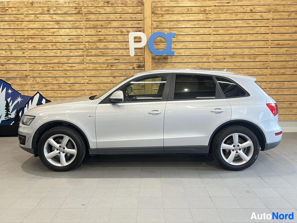 Sivulta: Hopeanharmaan Audi Q5:n sivuprofiili sisätiloissa, matkustamon puoleinen kylki kokonaan näkyvissä.