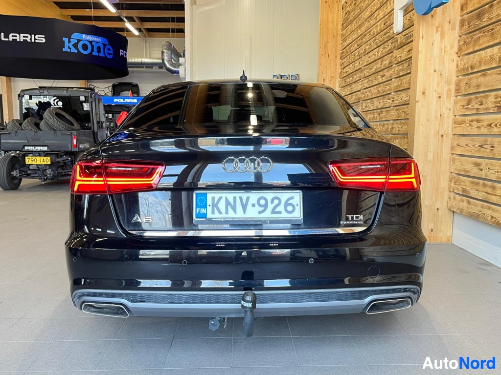 Takaa: Mustan sedanin takaosa suoraan edestä; Audi-merkki, taka­valot, rekisterikilpi, A6- ja TDI-merkinnät sekä irrotettava vetokoukku.