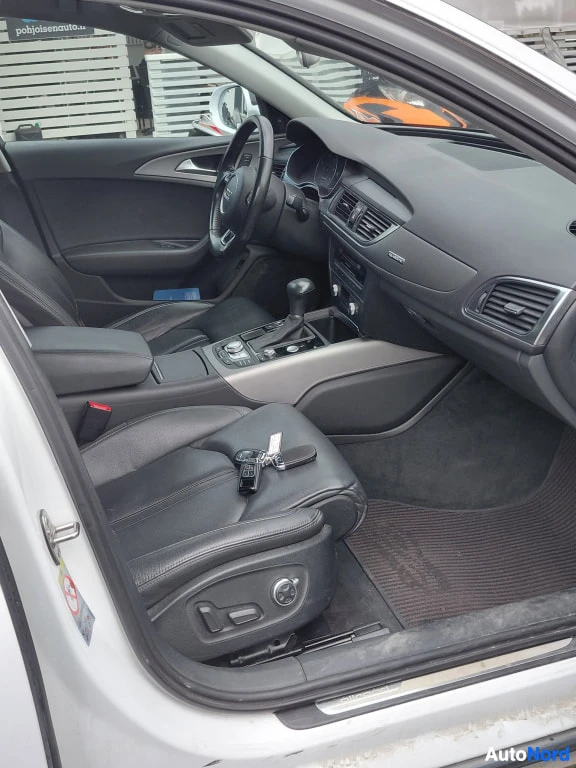 Muu: Mustan nahkaverhoiltu auton sisätila kuljettajan ovesta kuvattuna, avaimet penkillä.