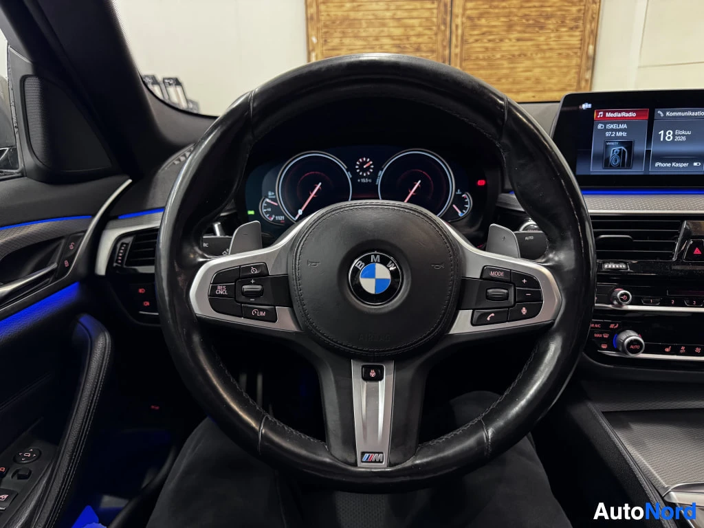 Muu: BMW-ohjauspyörä ja mittaristo edestä kuvattuna; M-merkitty ohjauspyörä ja näyttö, jossa lukee 18 Elkää 2026.