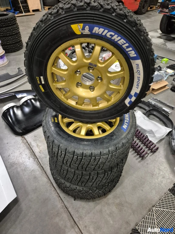 Yksityiskohta: Kaksi kultaista vanteista Michelin Pilot Sport -renkailla pinossa varastotilan lattialla.