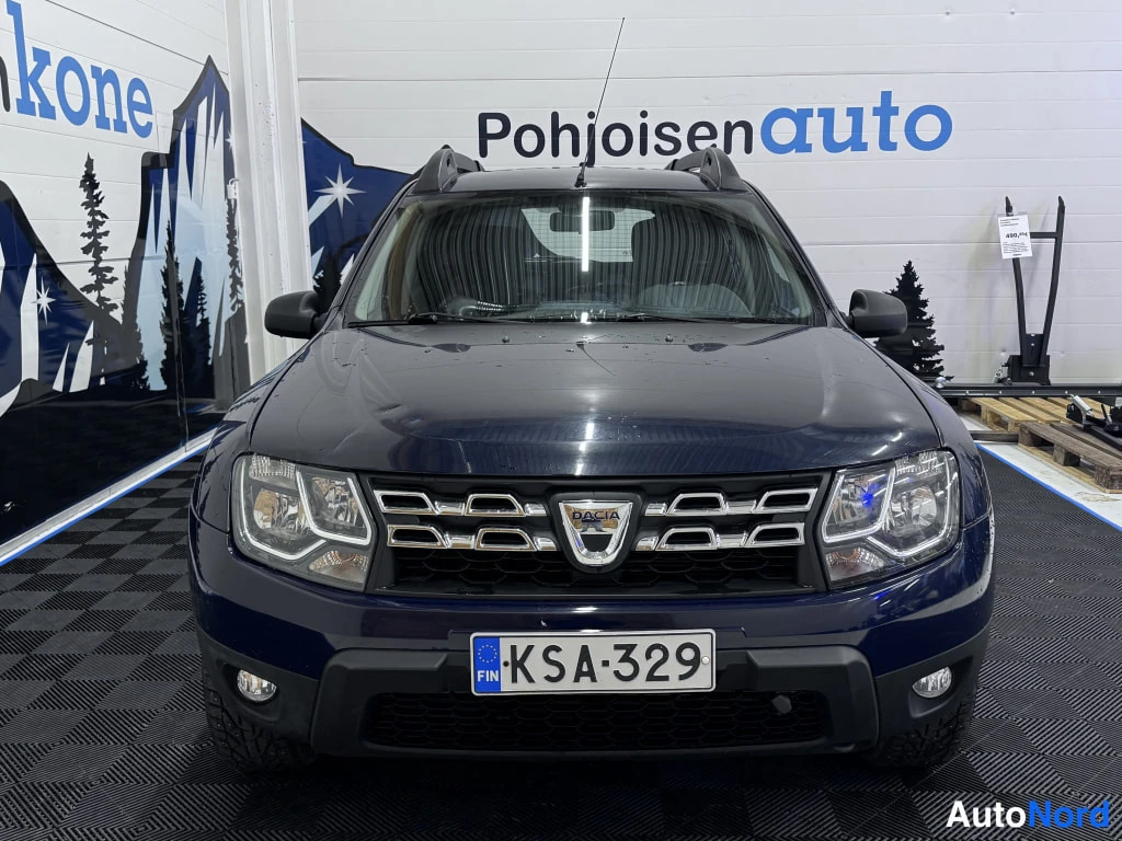 Edestä: Edustava kuva sinisestä Dacia Dusterista auton edestä. Autoon liittyy rekisterikilpi.
