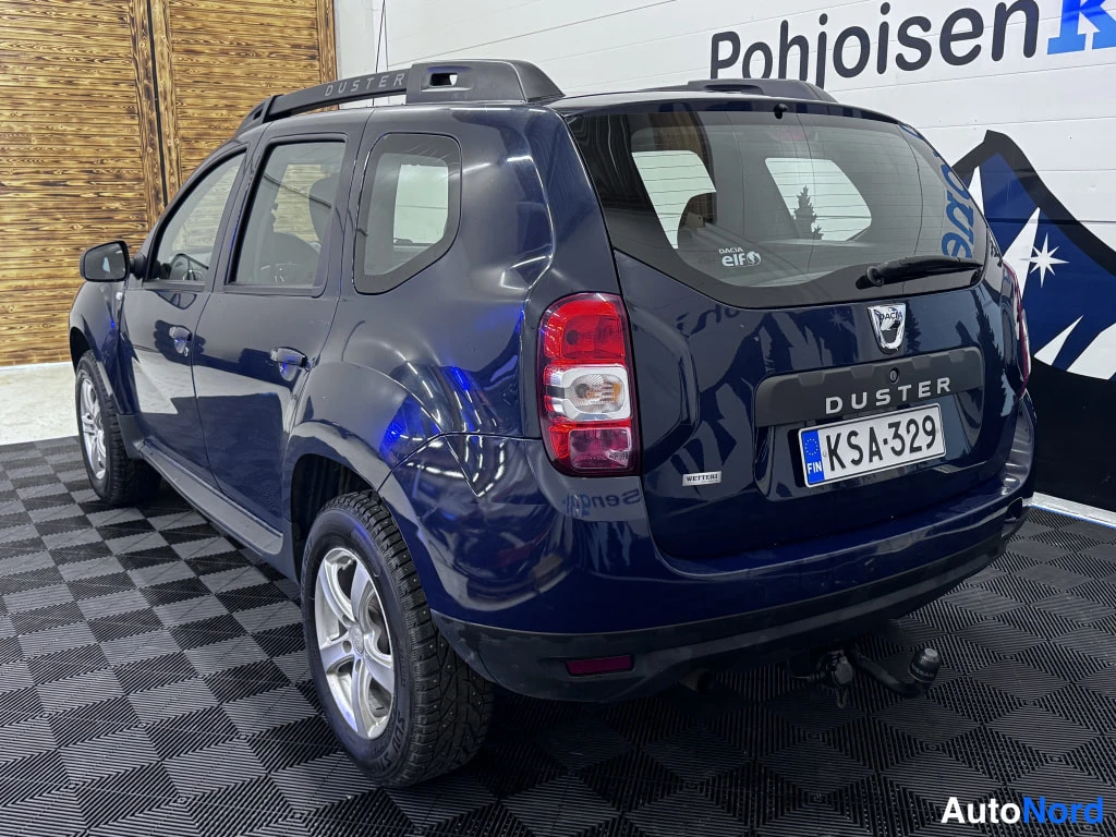 Takaviisto: Takaa kuvattu kuva sinisestä Dacia Dusterista. Rekisterikilpi on numero. Takana näkyvä vetokoukku on asennettu.