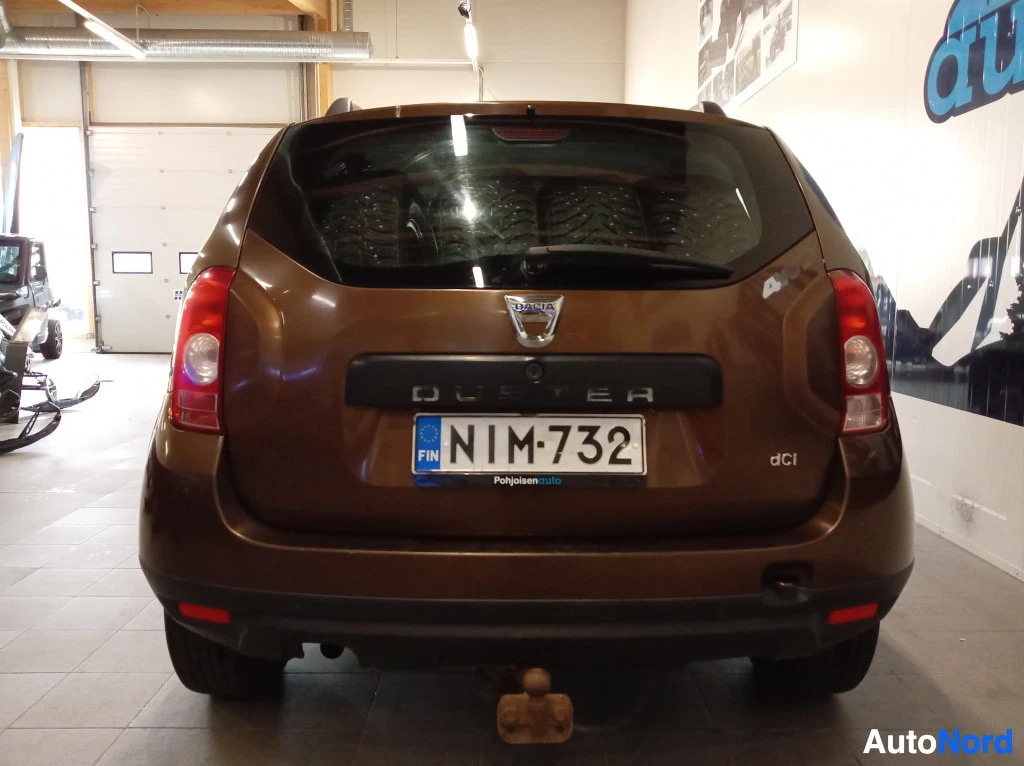 Takaa: Ruskean Dacia Dusterin takaosa suoraan takaa; DUSTER- ja dCi-tekstit, rekisterikilpi ja vetokoukku.
