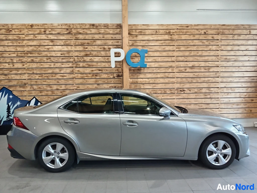 Sivulta: Lexus IS -sedanin sivukuva sisätiloissa; hopea koripaneelit, ovien kahvat ja alumiinivanteet näkyvissä.