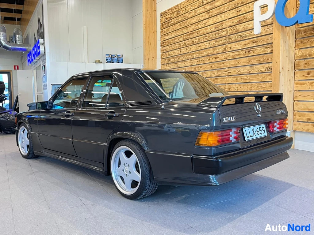 Takaviisto: Takakulmakuva tummansinisestä Mercedes 190E -henkilöautosta sisätiloissa, rekisteritunnus.