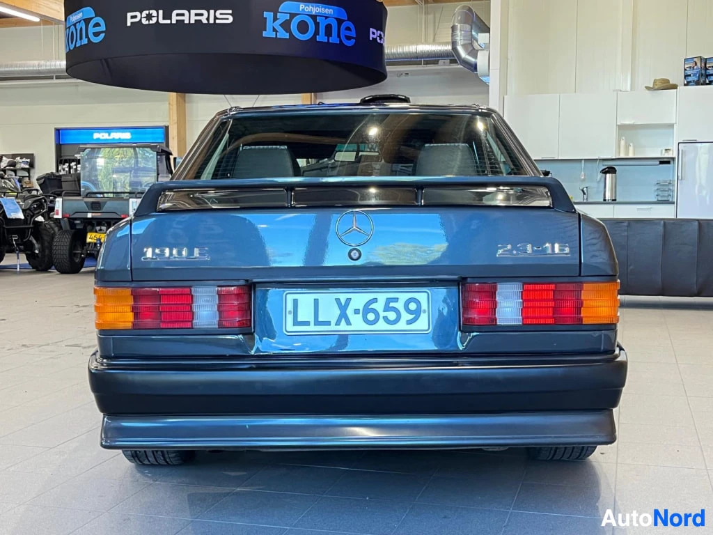 Takaa: Takaa kuvattu tummansininen Mercedes 190E 2.3-16 sisätiloissa, rekisteritunnus.
