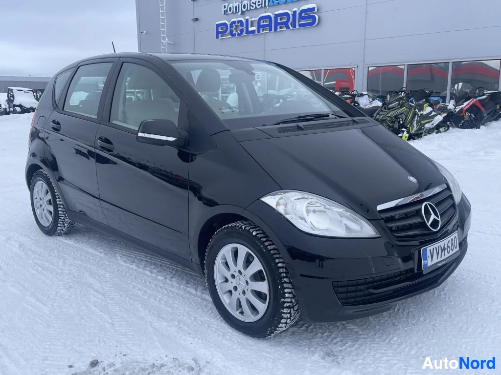 Etuviisto, nokka oikealle: Musta Mercedes-Benz A edestä oikealta kulmasta kuvattuna lumisella pihalla, rekisteritunnus.