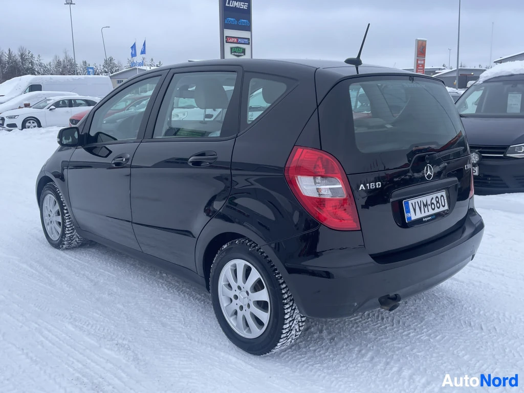 Takaviisto: Musta Mercedes-Benz A takaa oikealta kulmasta kuvattuna, takavalo ja -rekisterikilpi näkyvissä lumen keskellä.