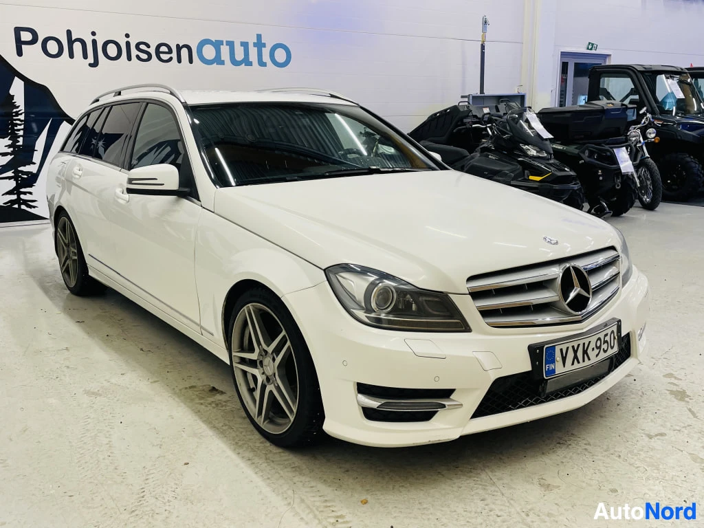 Etuviisto, nokka oikealle: Mercedes-Benz C-sarjan farmari etuviistosta oikealta, valkoinen kori ja AMG-tyyliset vanteet, rekisteritunnus.