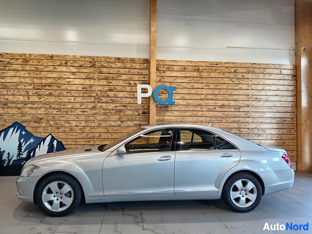 Sivulta: Hopeinen Mercedes-Benz S-sarjan sedan sivulta sisätiloissa.