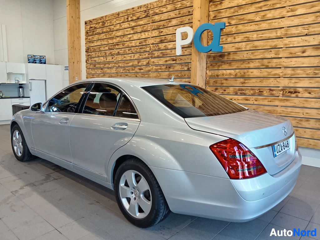 Takaviisto: Hopeinen Mercedes-Benz S-sarjan sedan takakulmasta sisätiloissa.