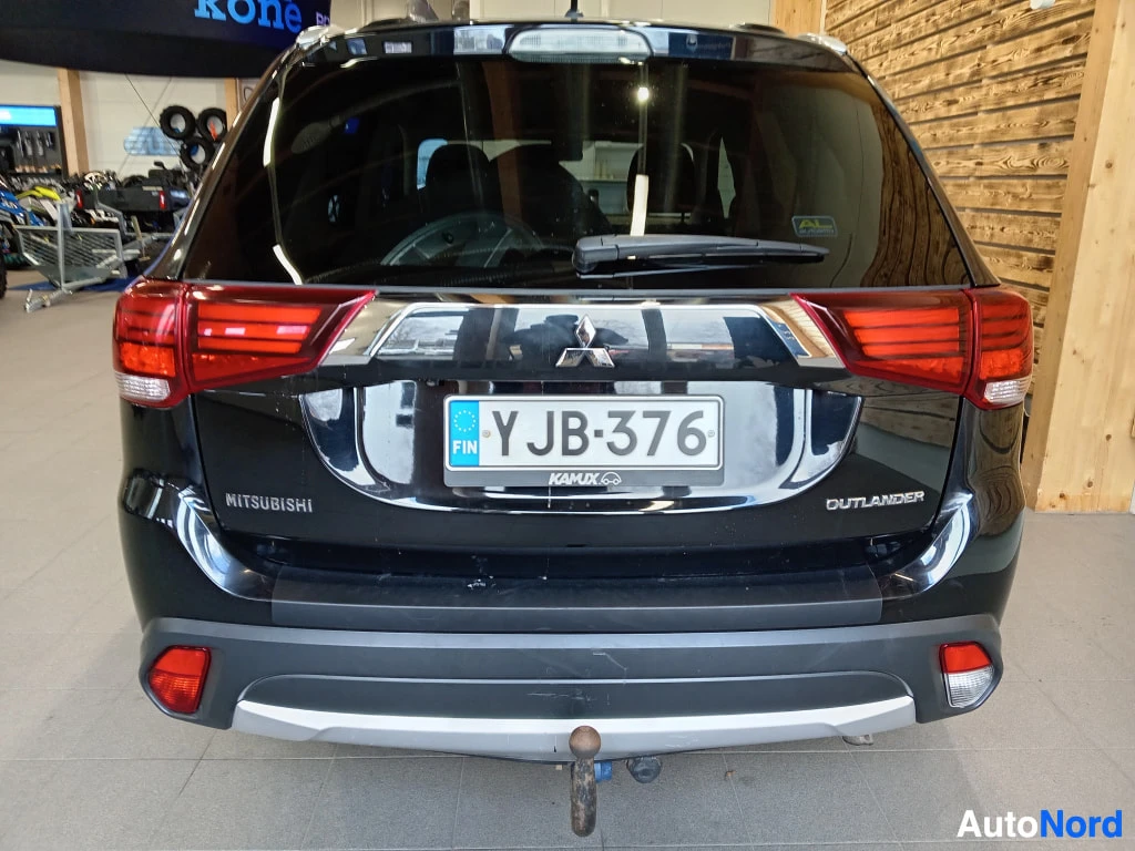Takaa: Mustan Mitsubishi Outlanderin takakuva sisätiloissa, rekisteritunnus.