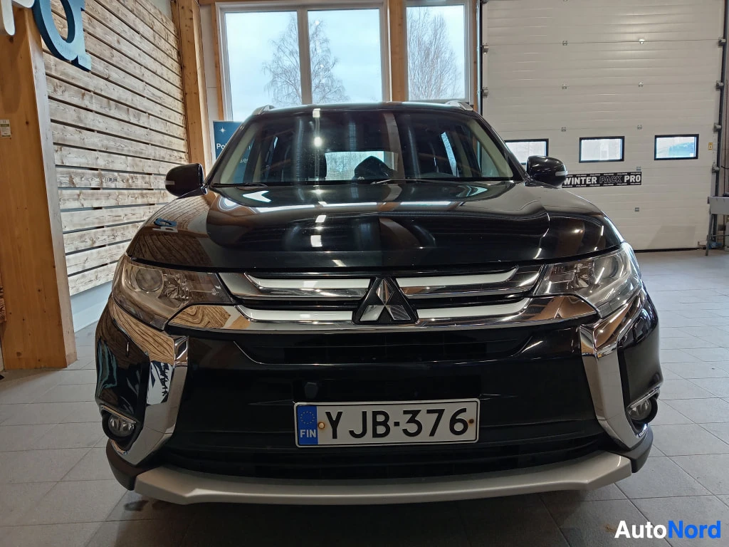 Edestä: Mustan Mitsubishi Outlanderin suoranainen etunäkymä sisätiloissa; etul Joint-Ovi löytyy rekisterikilven kohdalta rekisteritunnus.