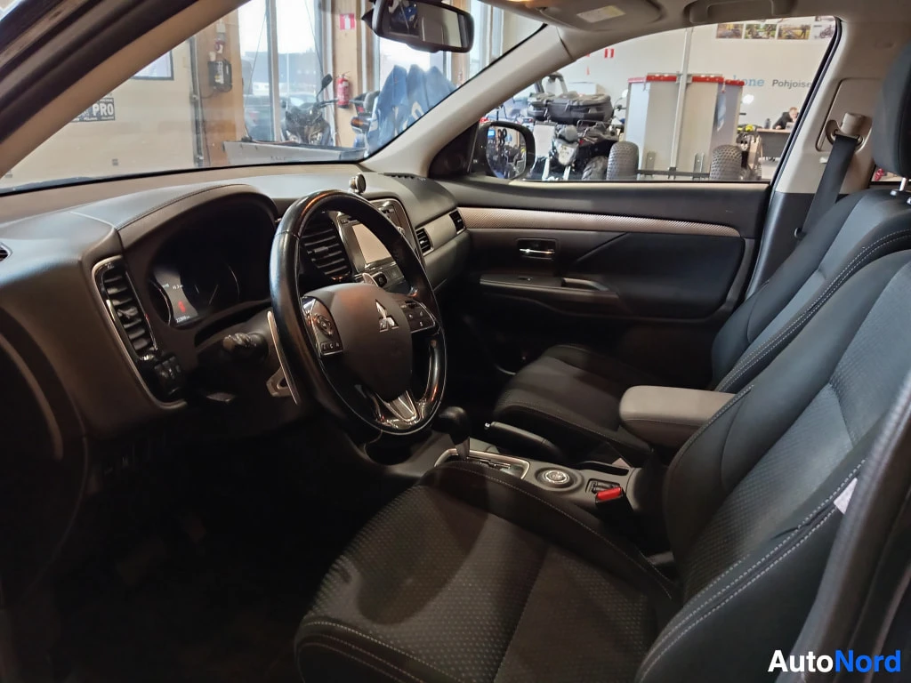 Ohjaamo: Ohjaamo etumatkustajan puolelta: Mitsubishi-ohjauspyörä, automaattivaihtajan valitsin ja tummat kangasistuimet.