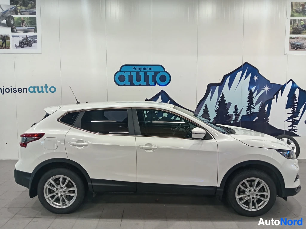 Etuviisto, nokka oikealle: Valkoinen Nissan Qashqai sivulta etukulmassa autonhallissa.