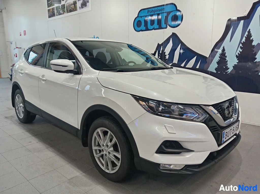 Etuviisto, nokka oikealle: Valkoinen Nissan Qashqai -henkinen farmurityylinen henkilöauto kuvattuna kolmannespystyöstä, keula vasemmalla, autotallissa.