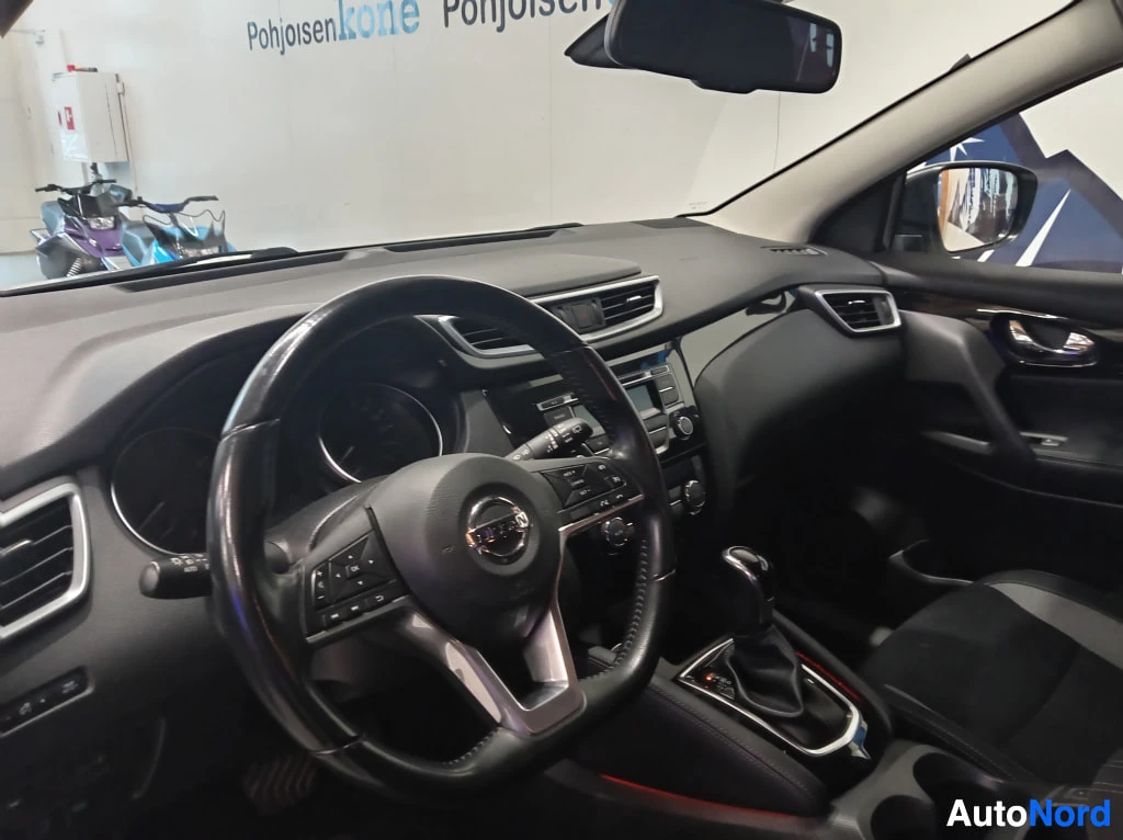 Muu: Lähikuva ohjauspyörästä ja kojelaudasta; Nissan-logomerkintä ohjauspyörässä ja automaattivaihteen valitsin.