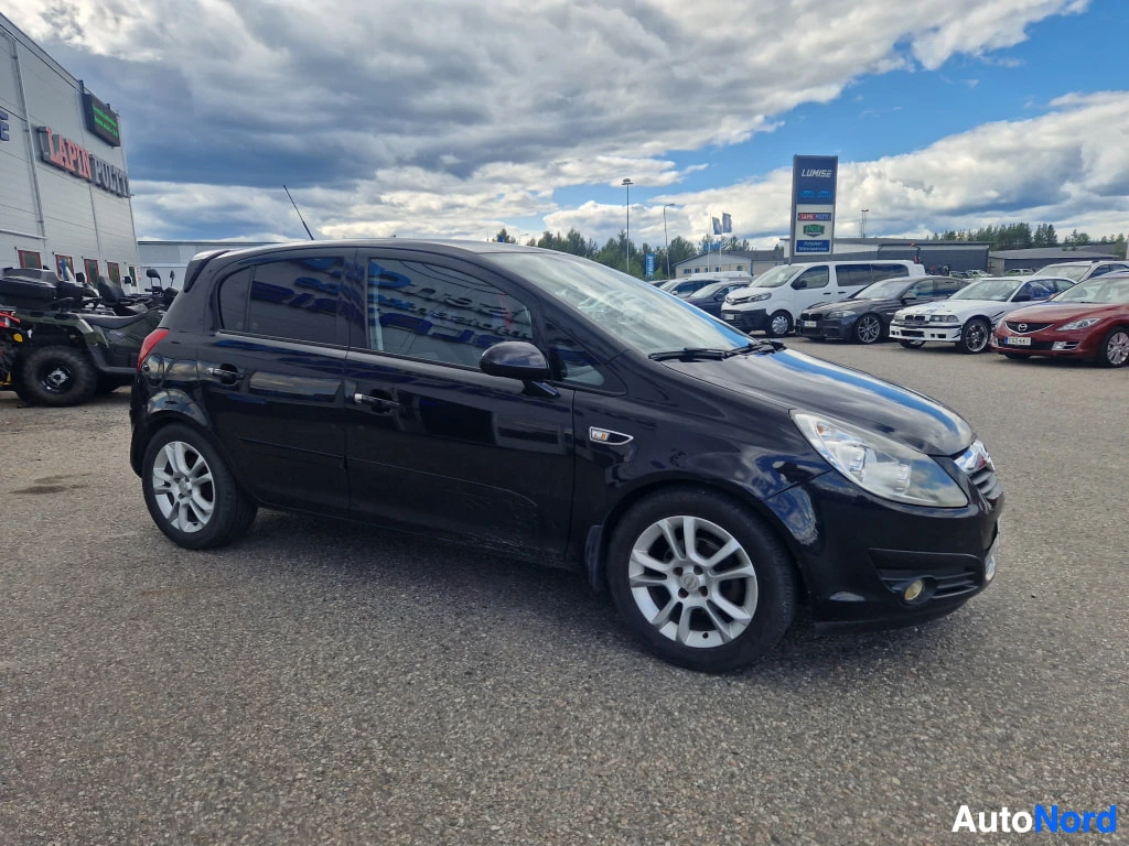 Etuviisto, nokka oikealle: Opel Corsa -henkilöauto edestä oikealta kolmannelta kuvattuna, musta.