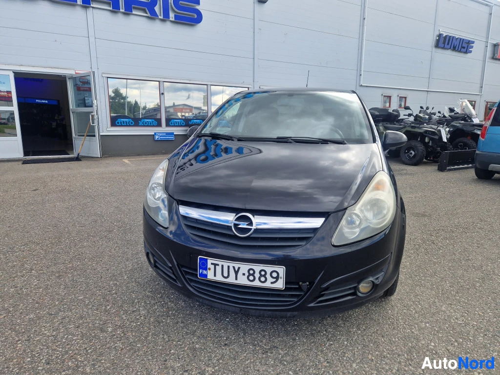 Edestä: Mustan henkilöauton etunäkymä, Opel-merkki etusäleikössä ja rekisterikilpi.