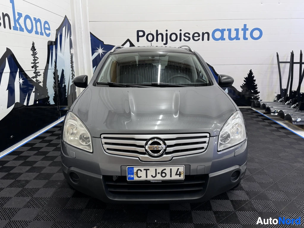 Edestä: Auton etunäyttö suoraan edestä: harmaa Nissan, etusäleikkö, Nissan-merkki ja rekisterikilpi.