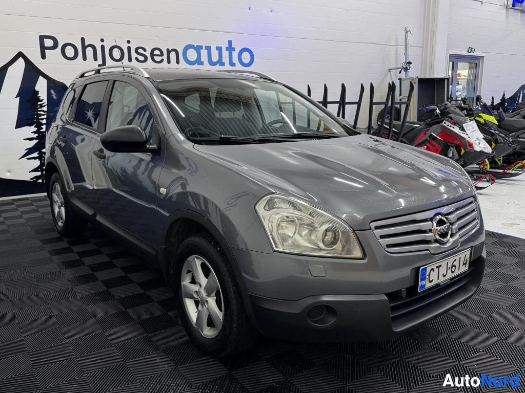 Etuviisto, nokka oikealle: Auton etukolmasosanäyttö oikealta: harmaa Nissan, etusäleikkö ja rekisterikilpi oikealla, vasen sivu näkyvissä.