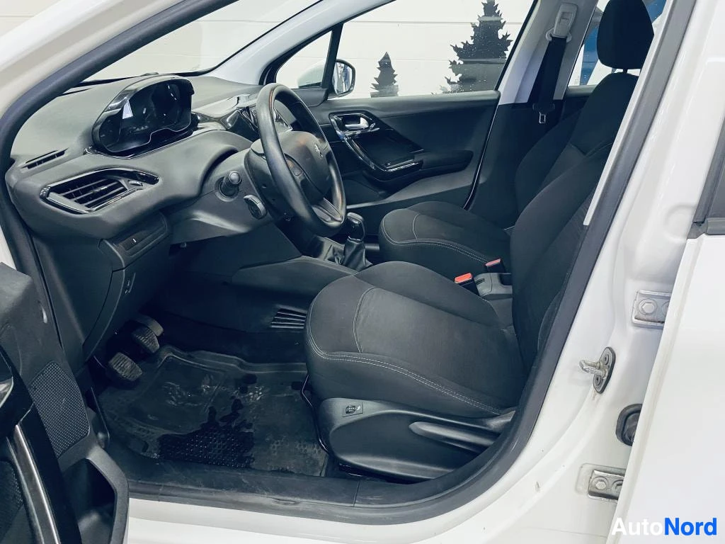 Muu: Avaudun kuljettajan oven sisäpuoli: mustat etupenkit, ohjauspyörä ja kojelauta, auto valkoinen.