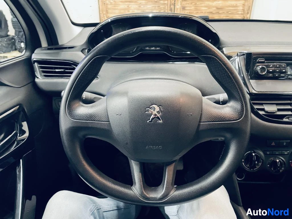 Muu: Ohjauspyörä Peugeot-logolla ja AIRBAG-tekstillä, taustalla mittaristo ja radio.