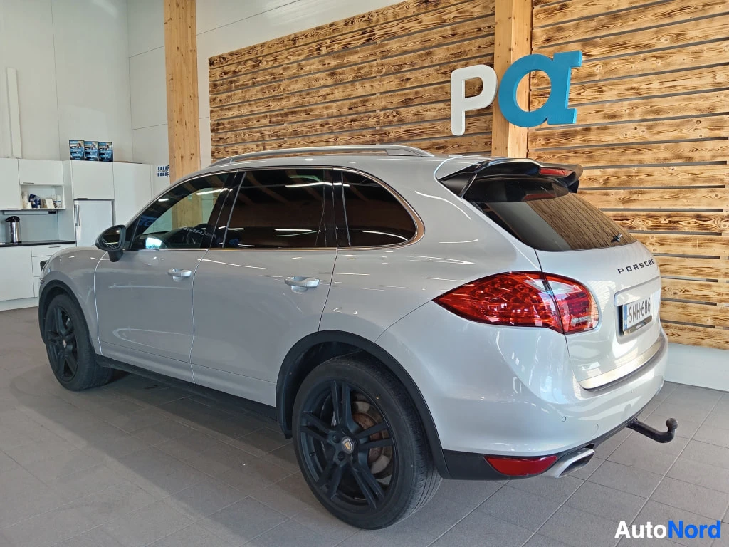 Takaviisto: Porsche Cayenne -maasturin takakulma kuvattuna oikealta, hopea koriväri, mustat kevytmetallivanteet, vetokoulu.