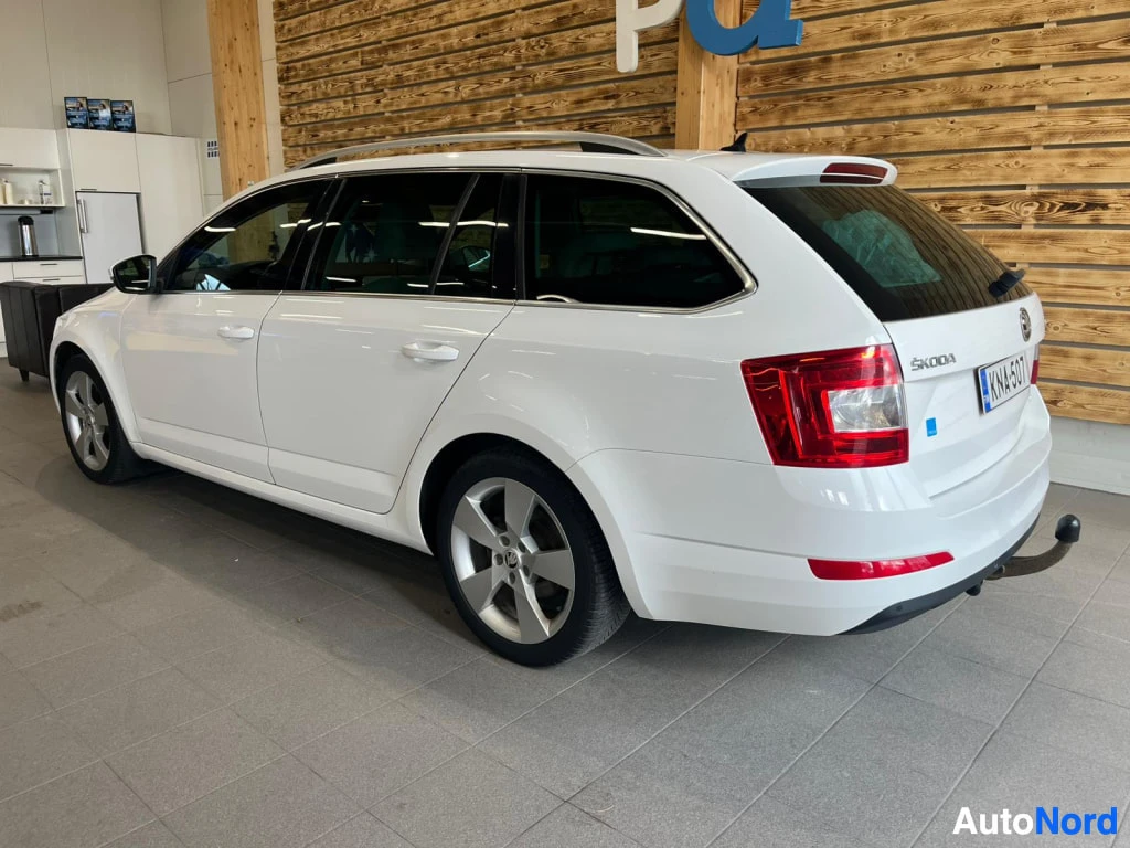 Takaviisto: Valkoinen Skoda Octavia Combi takaviisto vasemmalta, rekisteritunnus, vetokoulukoukku näkyvissä.