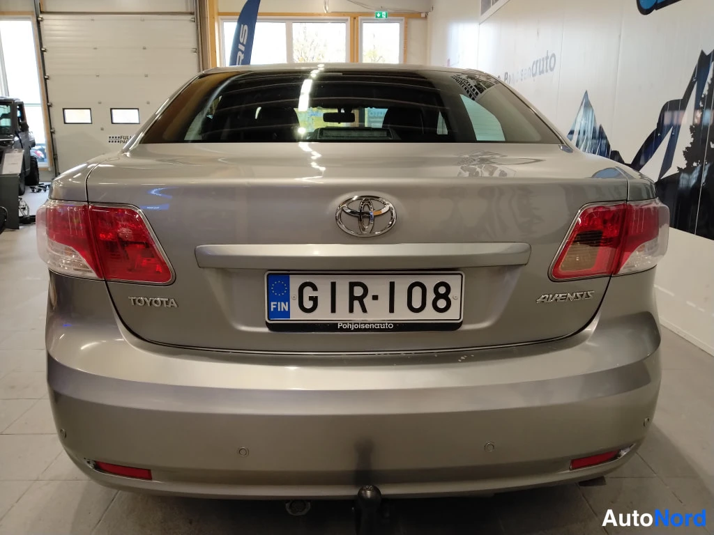Takaa: Toyota Avensis -sedanin takaosa suoraan takaa, rekisteritunnus, hopeisenharmaa kori.