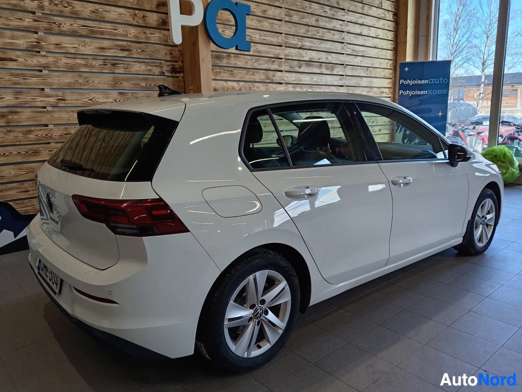 Takaviisto: Valkoinen Volkswagen Golf näkyy takaa ja oikealta sivulta. Auto on sijoitettuna sisätiloihin.