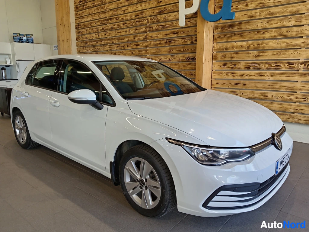 Etuviisto, nokka oikealle: Valkoinen Volkswagen Golf etualalla oikealta sivulta. Takavalojen ja takaluukun sijainnista päätellen auton edessä on oikea kylki. Auto on sijoitettuna n