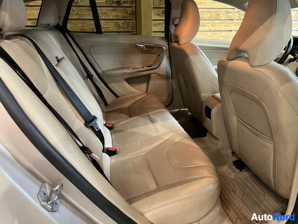 Takaistuimet: Volvo V60:n takaistuin sivulta katsottuna: beige-nahkainen jakkara, ovi auki, kaksi turvavyötä ja etuistuinten selkänojat.
