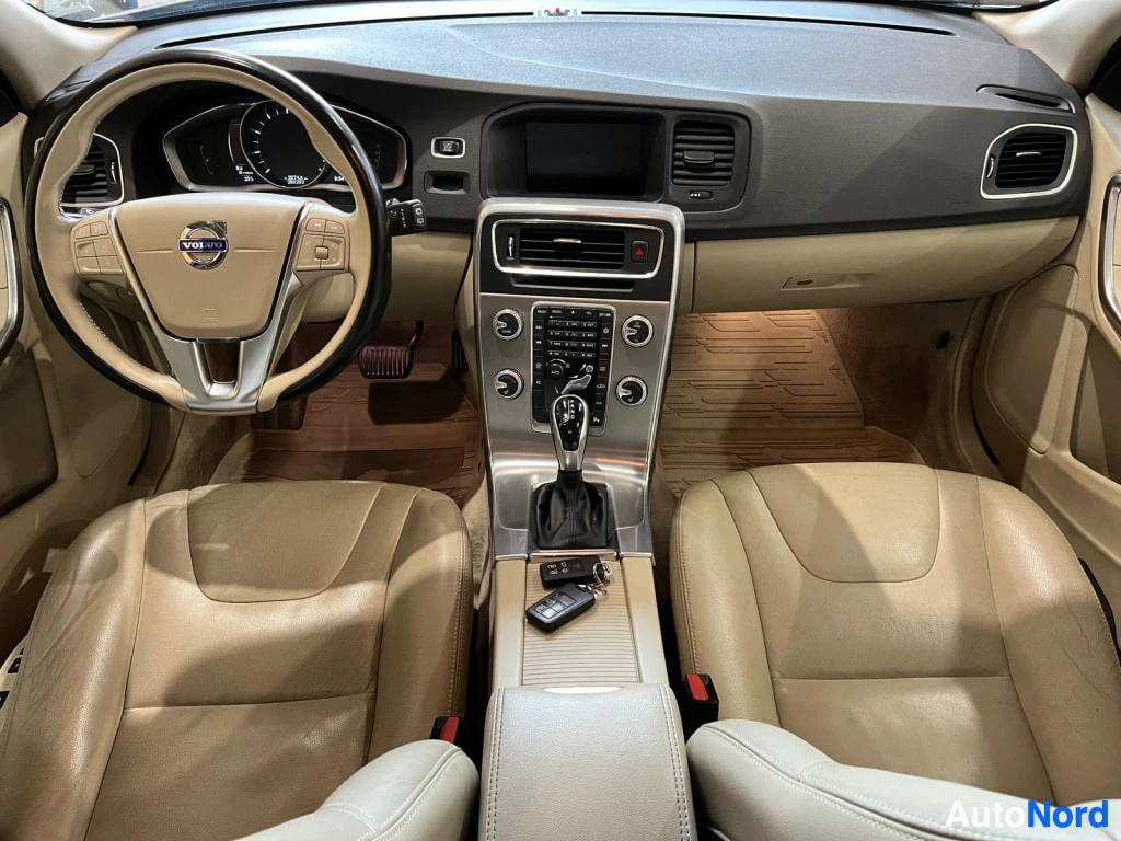 Muu: Volvo S60:n/v60:n sisätilat: vaalea nahkapanelointi, ohjauspyörä ja automaattivaihteisto.
