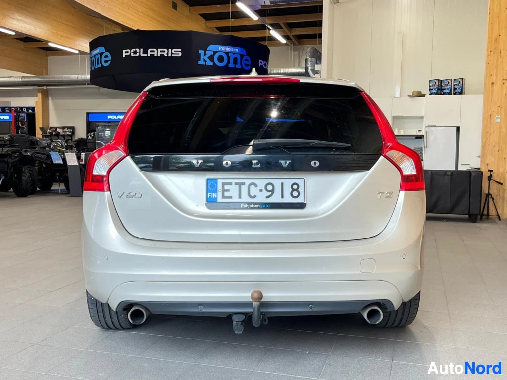 Takaa: Farmariauton takaosa suoraan takaa kuvattuna, rekisterikilpi, VOLVO-, V60- ja T3-tekstit, kaksi pakoputkea ja vetokoukku näkyvät.