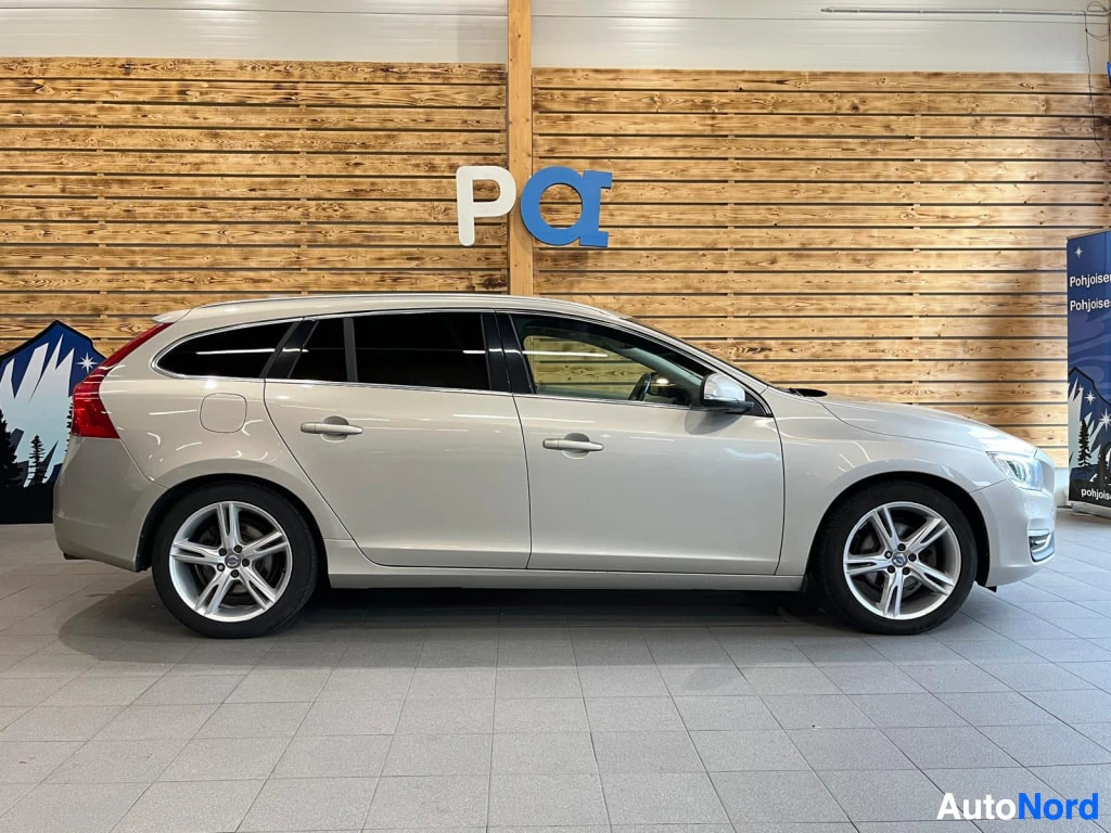 Sivulta: Vaaleanbeigen Volvo V60 -farmarin kylki sivulta kuvattuna sisätiloissa; viidellä ovella ja hopeavanteilla.