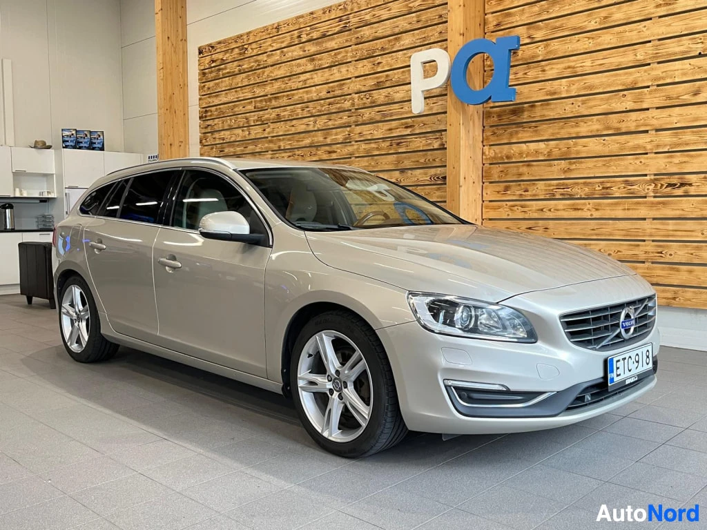 Etuviisto, nokka oikealle: Volvo V60 -farmarin etukulma sisätiloissa; keulagrafiikka ja rekisterikilpi näkyvät oikealla.