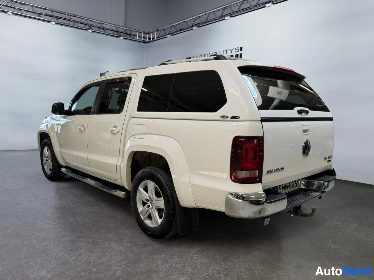 Takaviisto: Valkoinen Volkswagen Amarok -lakana-auton takaosa ja vasen kylki kuvattuna takaa, takana kuplu ja vetoaisa.