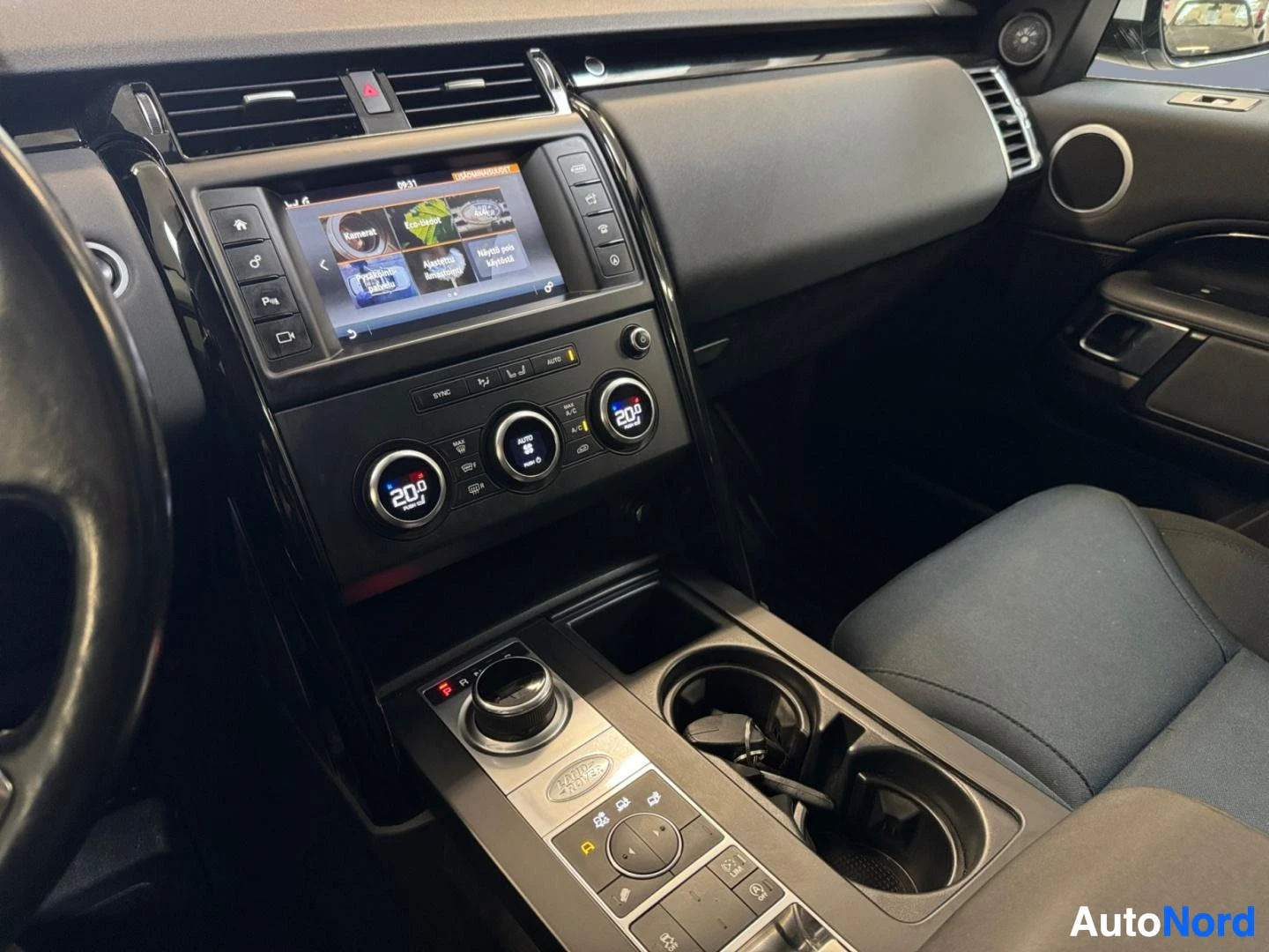 Etuistuimet: Center console showing infotainment screen, climate control knobs and drive mode selector.