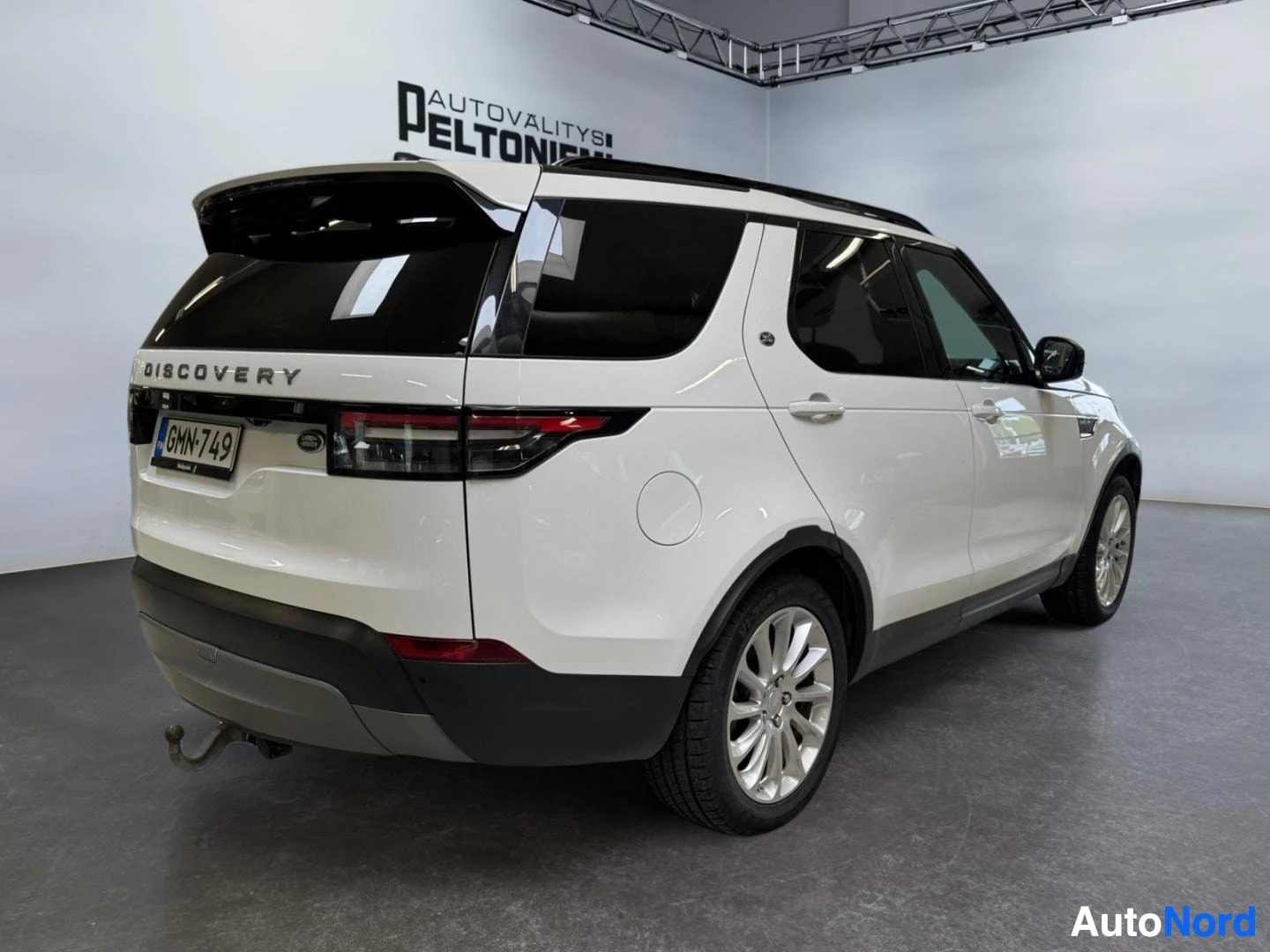 Takaviisto: Valkoinen Land Rover Discovery takakulmasta, rekisteritunnus, perävaunukoulu näkyvissä.