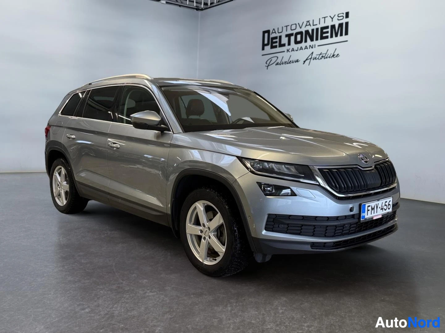 Etuviisto, nokka oikealle: Hopeanharmaa Skoda Kodiaq -maasturin etukulmanosto sisätiloissa, rekisteritunnus.