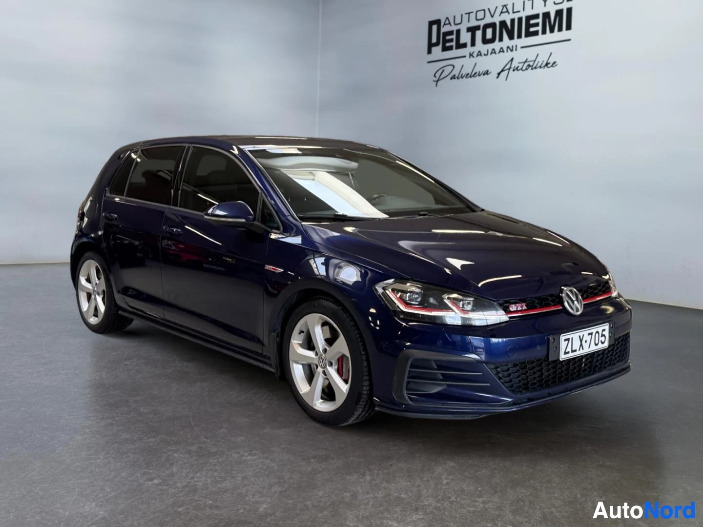 Etuviisto, nokka oikealle: Sininen Volkswagen Golf GTI-merkinnöin kuvattu kolmivartalo-frontend-kuvakulmasta, keula oikealla, rekisteritunnus.